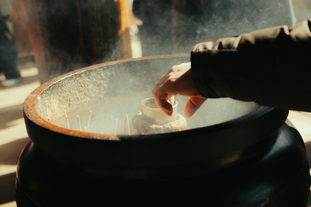 A cooking creator filming a close-up of sizzling food in a pan with a macro lens attachment