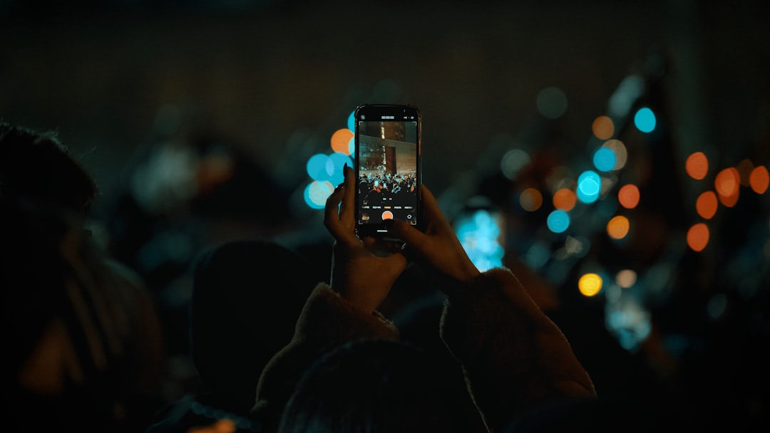 A person recording an event on their iPhone in a crowd